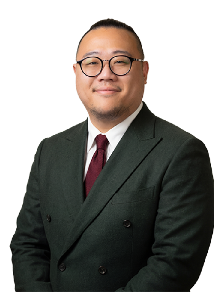 A professional studio portrait of Mr Chad Chang, a consultant surgeon specialising in lymphatic supermicrosurgery, wearing a dark green double-breasted suit, a white shirt, a maroon tie, and glasses.