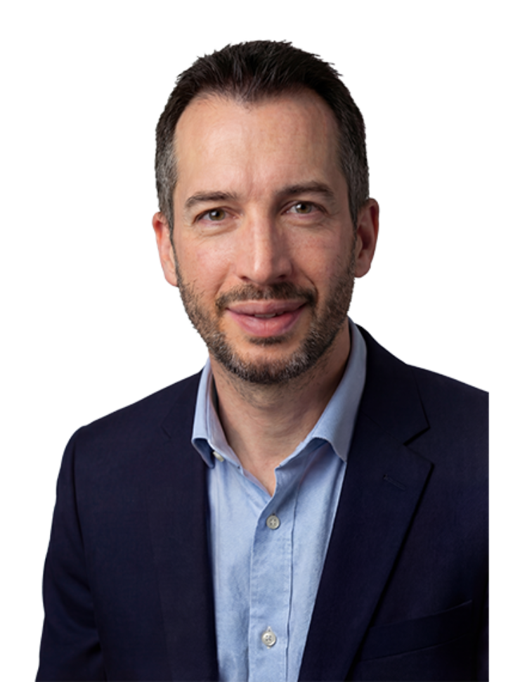 A professional studio portrait of consultant surgeon Mr John Henton, FRCS(Plast), at the Great North Lymphatic Centre, wearing a navy blue blazer and a light blue button-down shirt.